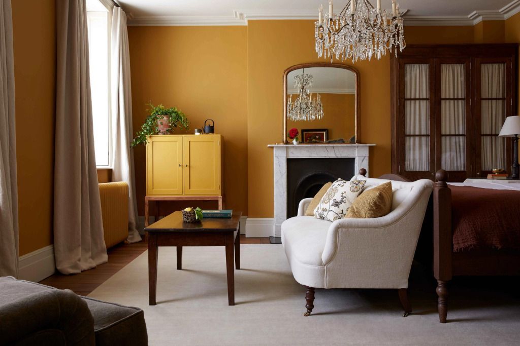 Eleganter Wohnbereich mit gelben Akzentwänden und Kristallleuchter in der Suite