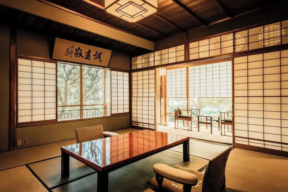 Japanisches Wohnzimmer im Hiiragiya Ryokan mit großem Holztisch und Shōji-Trennwänden.
