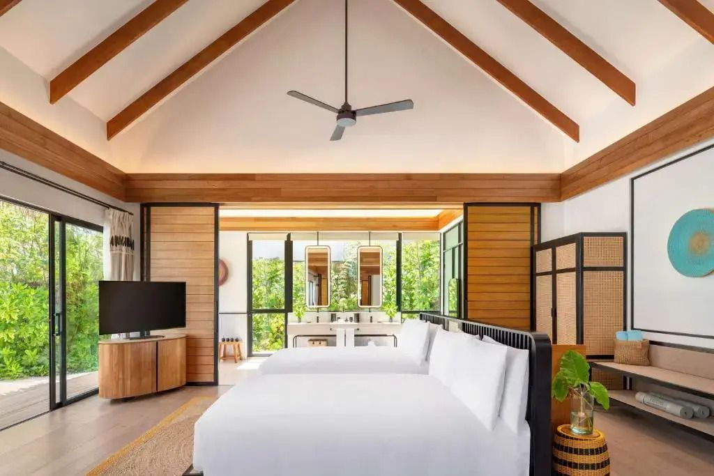 Helles Schlafzimmer mit hohen Decken und zwei Betten im Hilton Maldives Amingiri Resort.