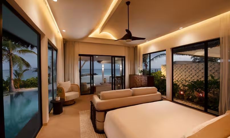 Schlafzimmer mit Doppelbett und Blick auf die Terrasse und das Meer bei Abenddämmerung.