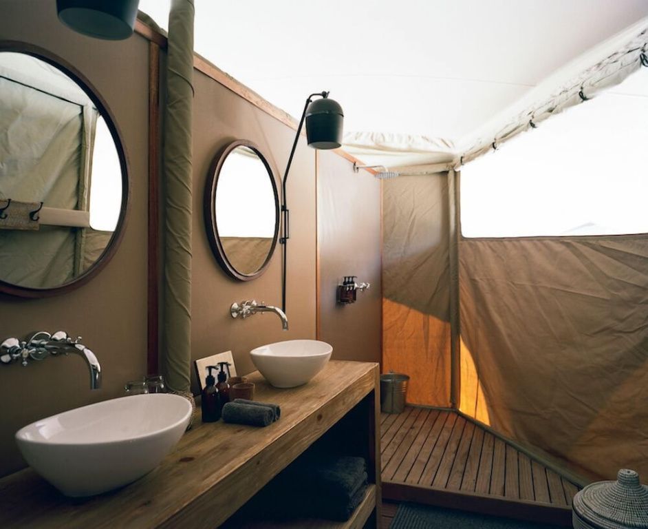 Innenansicht eines luxuriösen Zeltes mit Doppelwaschbecken und Holzelementen im Hoanib Valley Camp