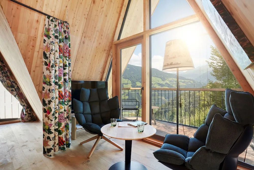Gemütlicher Wohnbereich mit Panoramablick auf die Alpen durch große Fenster.