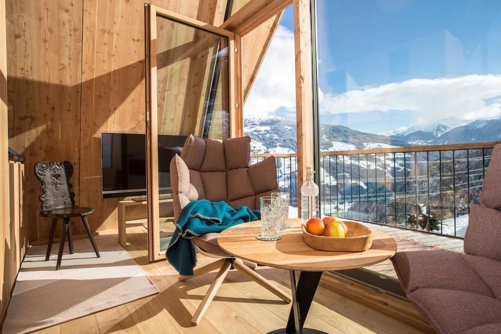 Wohnbereich mit großem Fenster und Blick auf schneebedeckte Berge.