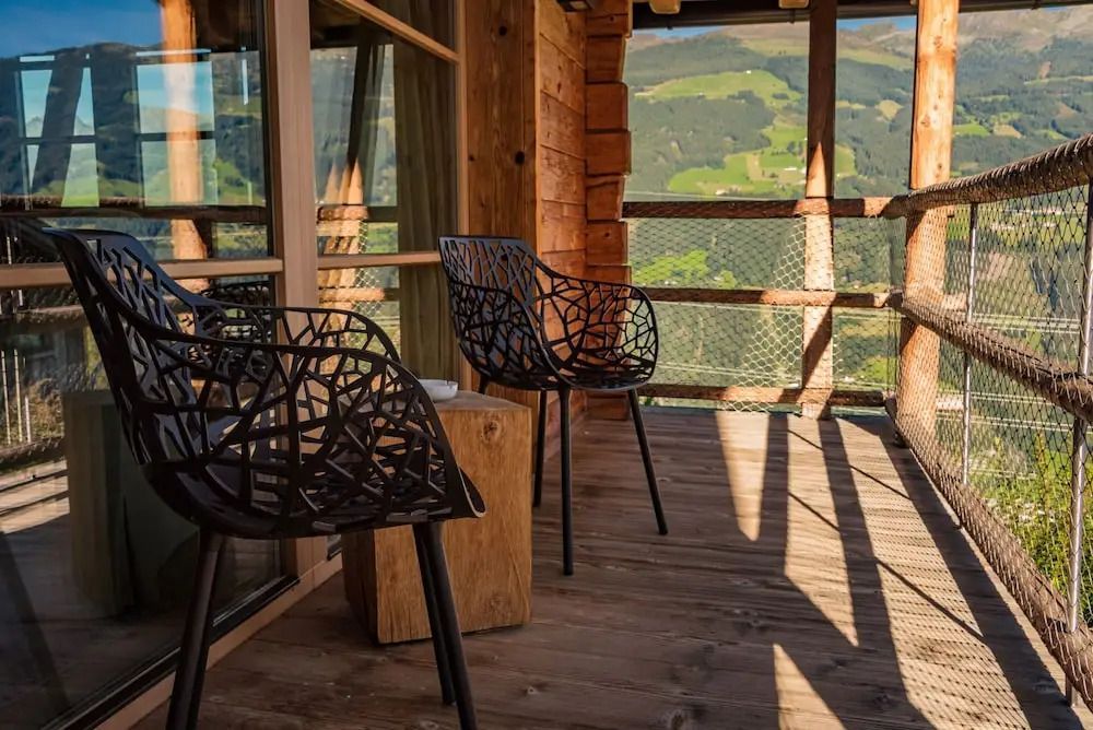 Holzbalkon mit Blick auf die Alpen und zwei Design-Stühlen