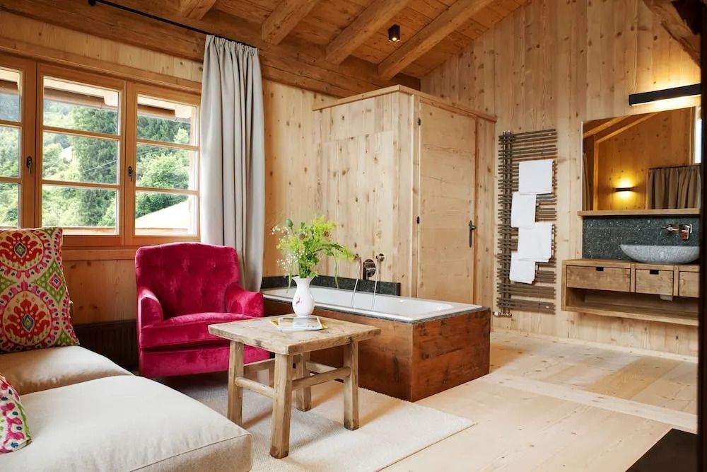 Gemütliches Zimmer mit freistehender Badewanne und rotem Sessel