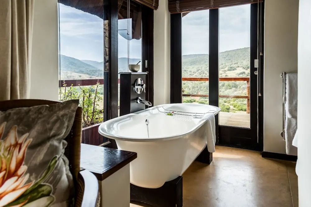 Luxuriöses Bad mit freistehender Wanne und Blick auf grüne Landschaft im Hotelzimmer