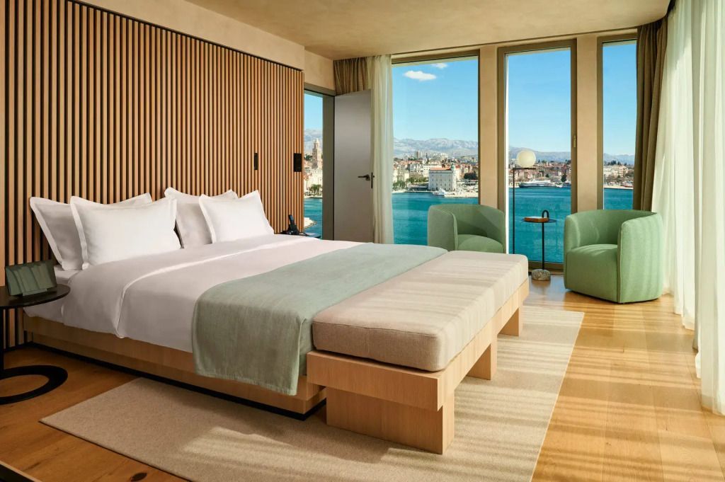 Sonnendurchflutete Suite mit Doppelbett und Meerblick durch große Fenster