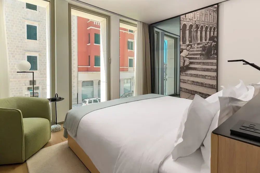 Doppelzimmer mit moderner Einrichtung und großer Fensterfront zur Straße.