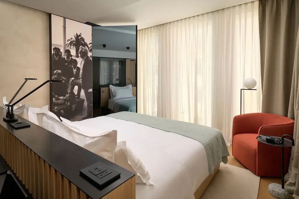 Modernes Zimmer mit Doppelbett, Kunst an der Wand und lichtdurchlässigen Vorhängen.
