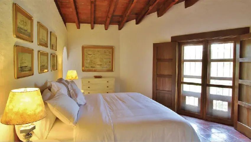 Gemütliches Schlafzimmer mit Holzbalkendecke und einem großen Bett in neutralen Farben.