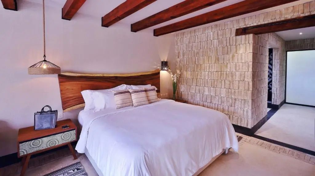 Komfortables Bett im Premium Doppelzimmer mit dekorativer Steinwand