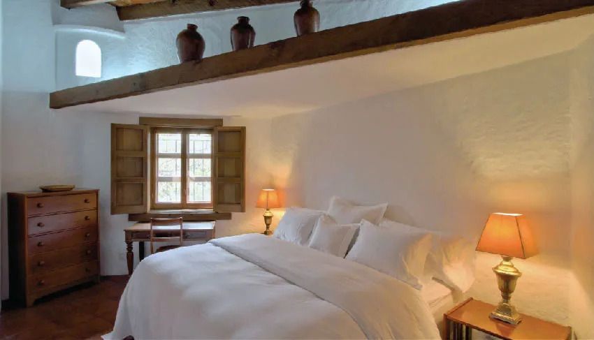 Rustikales Schlafzimmer mit Holzbalken und antikem Fenster