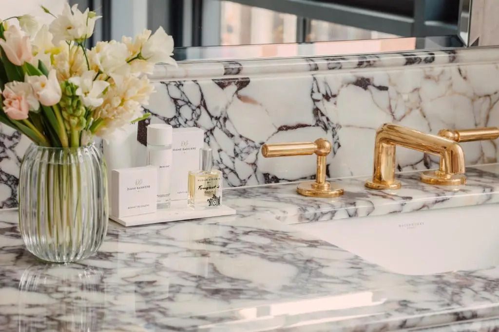 Luxuriöses Badezimmer mit Marmorwaschbecken und goldenen Armaturen