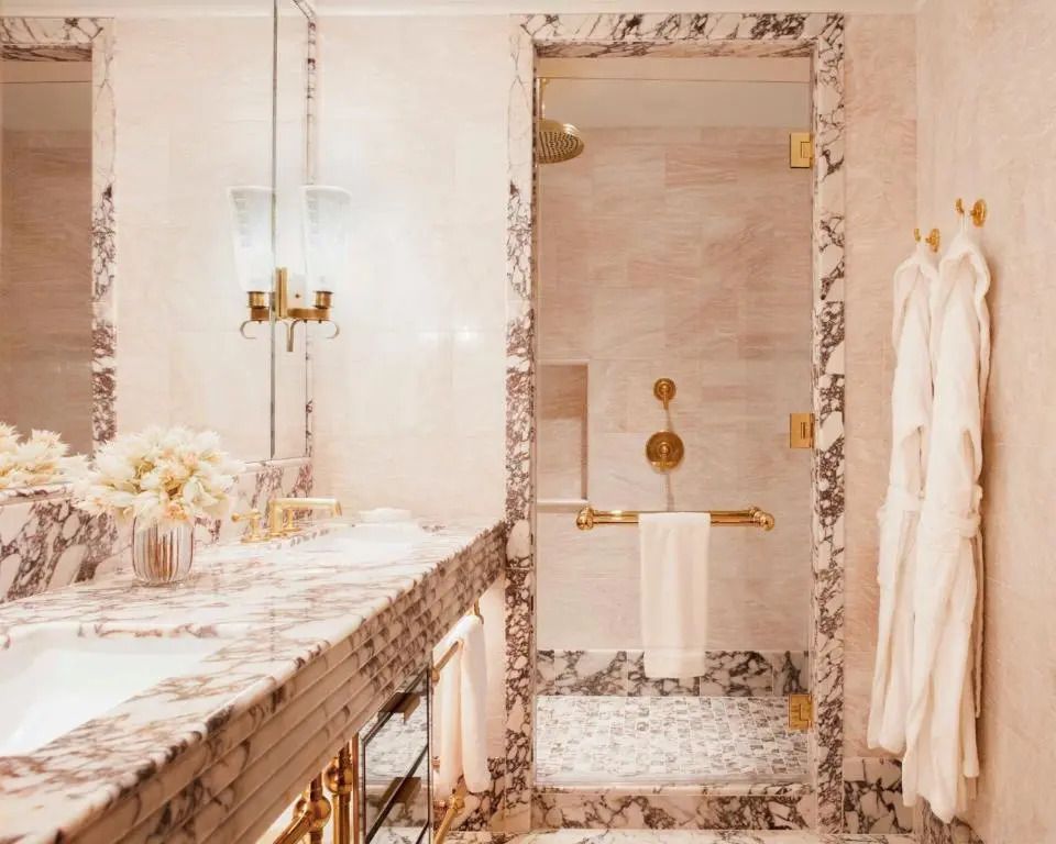 Hochwertiges Badezimmer mit Marmorakzenten und goldenen Armaturen.