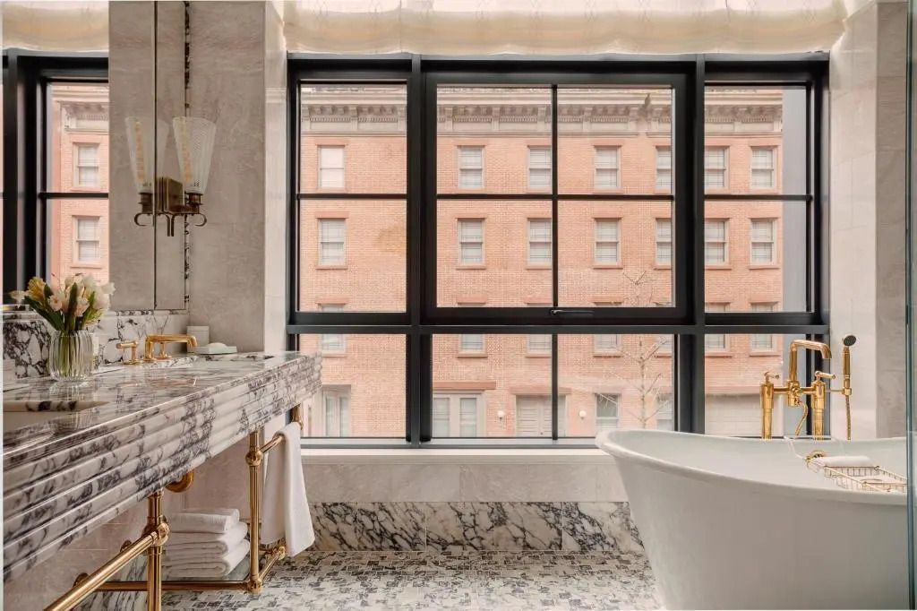 Luxuriöses Badezimmer mit freistehender Badewanne und großen Fenstern.
