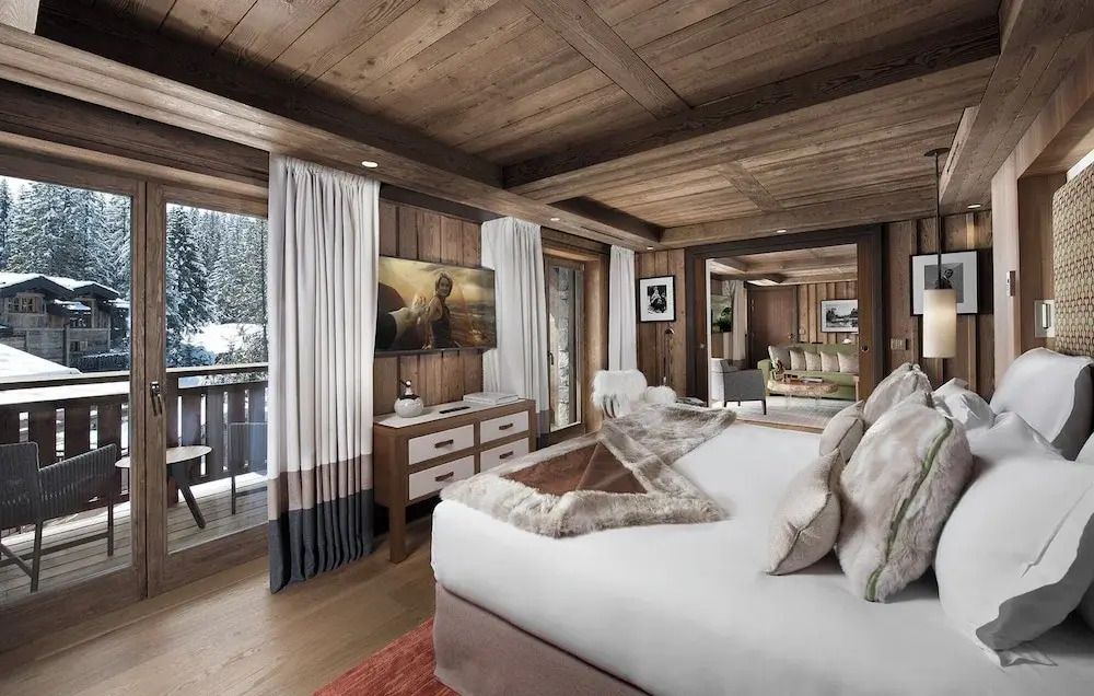Geräumiges Schlafzimmer der Deluxe Suite mit Zugang zu einem Balkon und Blick auf die Berge