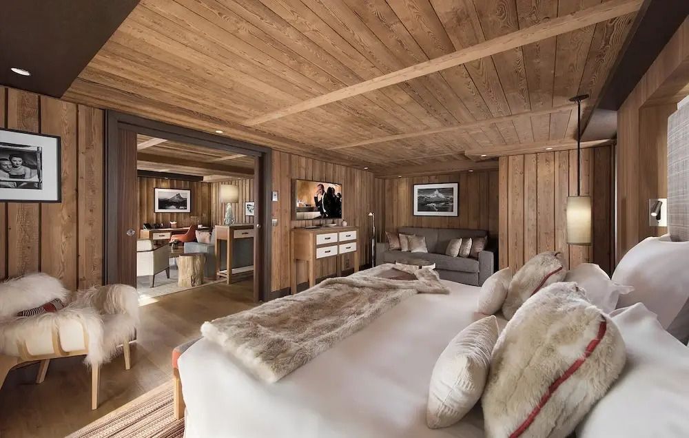 Einladendes Schlafzimmer der Deluxe Suite mit Holzvertäfelung und Blick ins Wohnzimmer