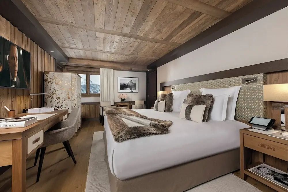 Luxuriöses Schlafzimmer mit Holzbalkendecke und stilvollen Fellakzenten.