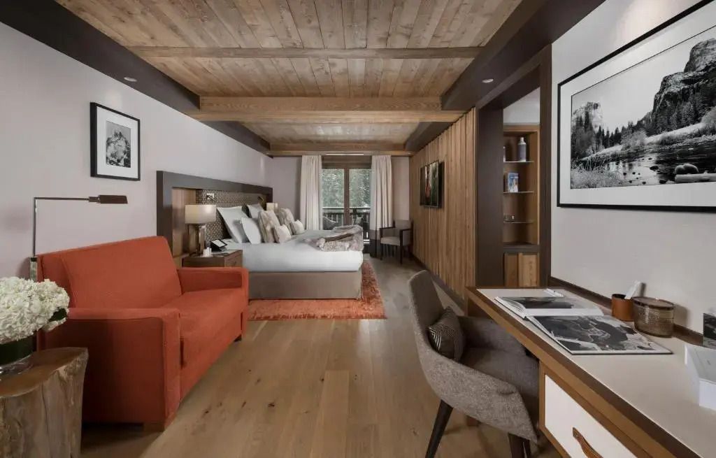 Junior-Suite mit großem Bett und stilvollem Holzdesign sowie einem gemütlichen Sitzbereich
