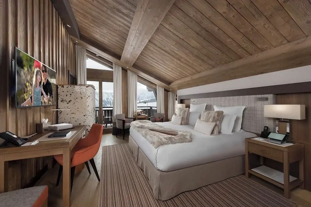 Geräumiges Zimmer mit Doppelbett, Schreibtisch und Bergblick durch große Fenster.