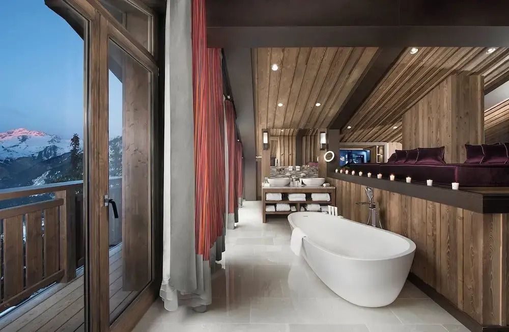 Luxuriöses Badezimmer mit freistehender Badewanne und Blick auf den Balkon.