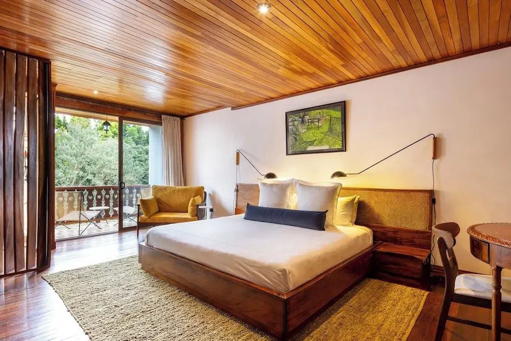 Standard Zimmer mit Balkon Holzelementen hellem Bett und Sitzbereich