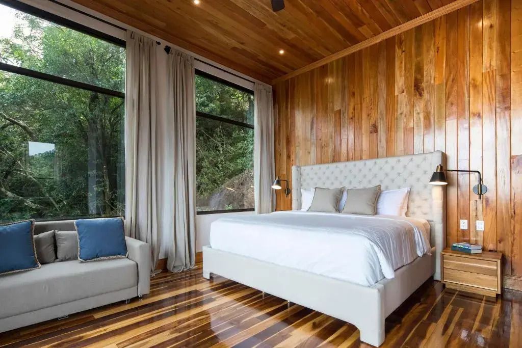 Helles Schlafzimmer mit Holzwänden und großen Fenstern