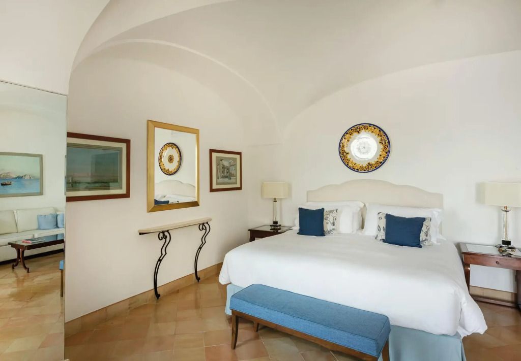 Elegant eingerichtetes Schlafzimmer mit blauem Sofa und Kunstwerken.