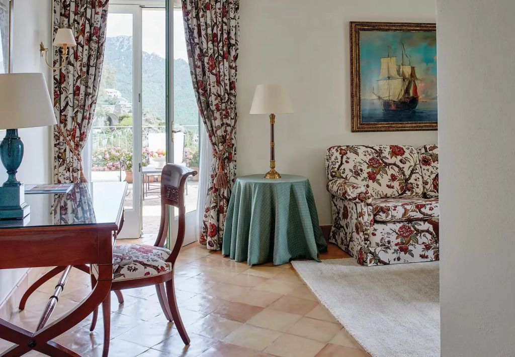 Wohnbereich mit floralen Möbeln und Zugang zur Terrasse im Caruso Hotel