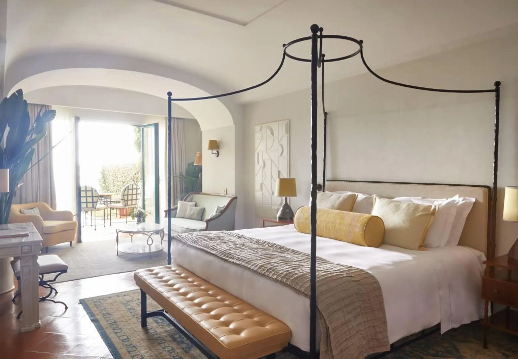 Lichtdurchflutete Suite mit elegantem Himmelbett und Meerblick von der Terrasse.