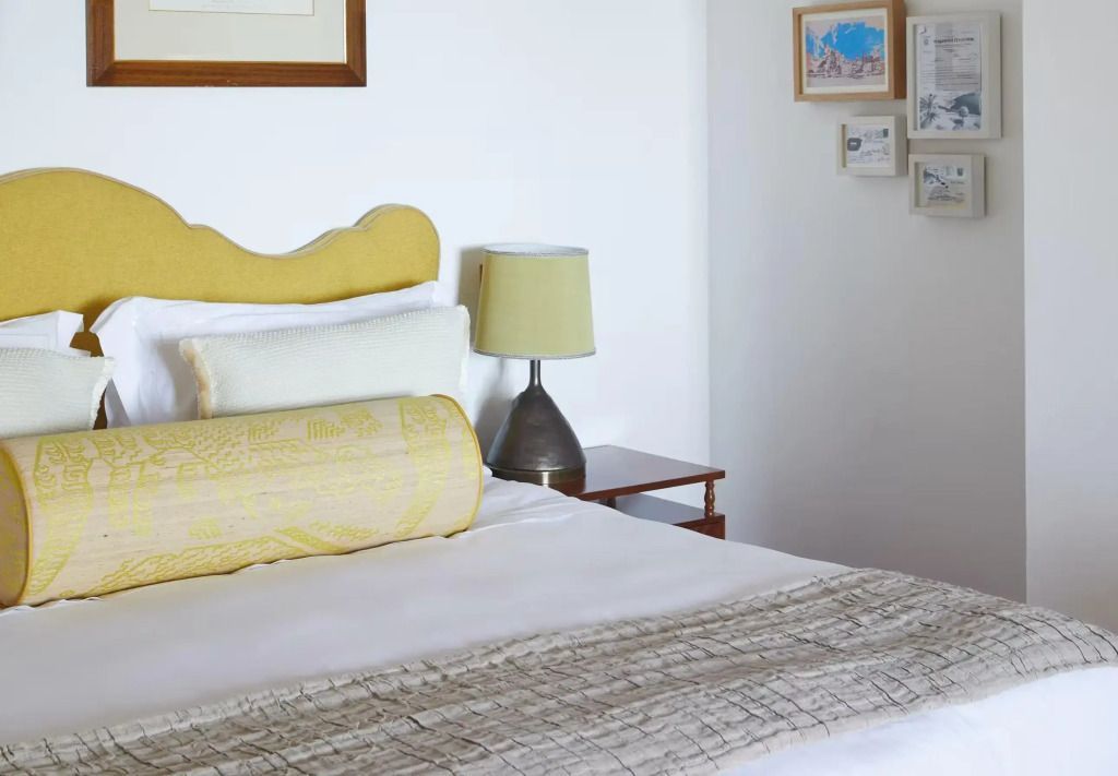 Hell eingerichtetes Schlafzimmer mit elegantem Doppelbett und gelbem Kopfteil