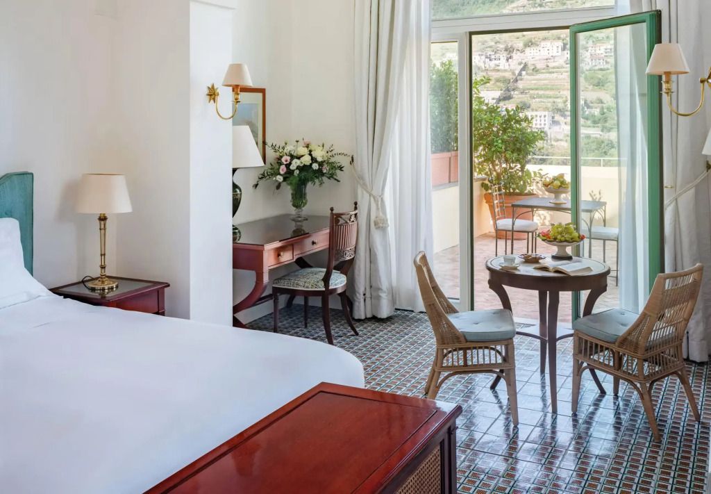 Helles Zimmer mit Doppelbett, Balkon mit Blick auf Berge, elegante Möbel.