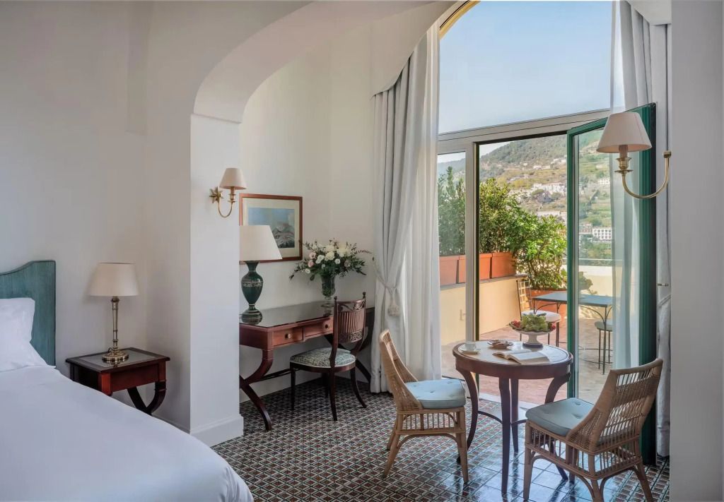 Komfortabel eingerichtetes Zimmer mit offenem Balkon und landschaftlichem Ausblick.