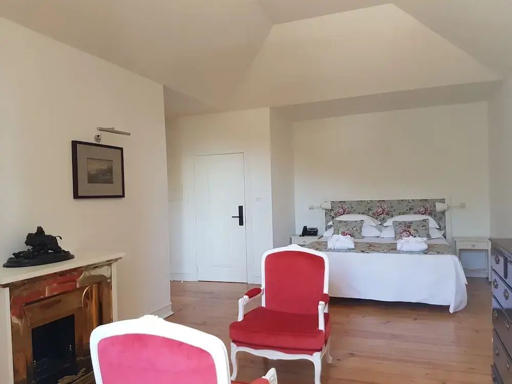 Suite mit roten Sesseln und großzügigem Bett in gepolstertem Kopfteil