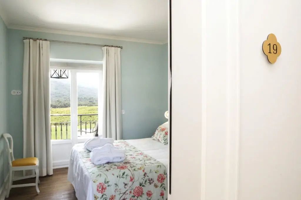 Helles Premium-Zimmer mit floralem Bettbezug und Balkonblick auf die Berge.
