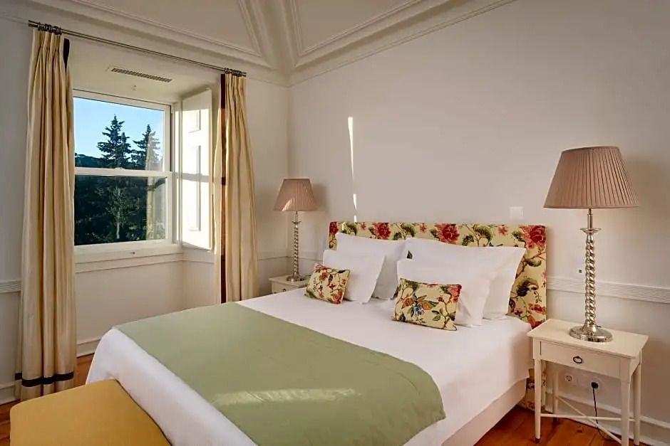 Gemütliches Bett mit farbenfroher Kopfleiste und großen Fenstern