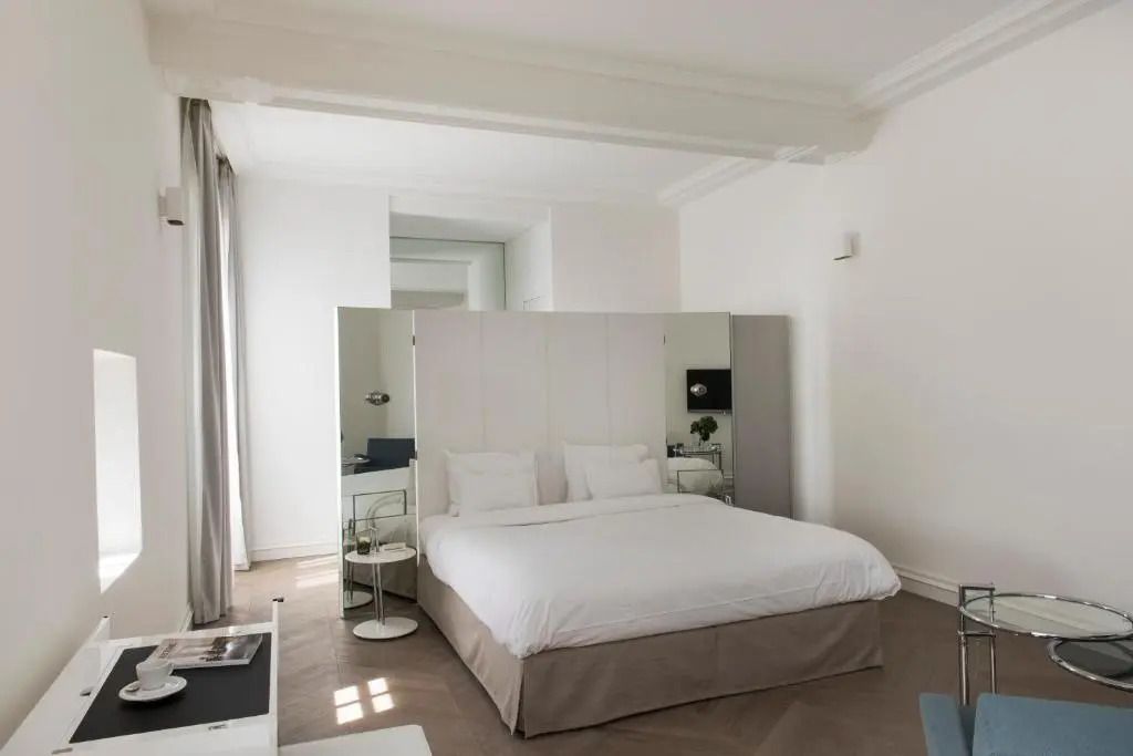 Helles Schlafzimmer mit großem Bett und Fenstern mit Vorhängen