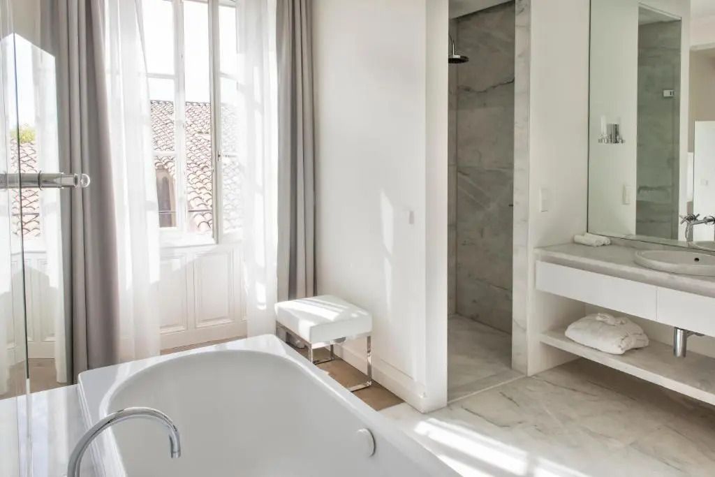 Badezimmer mit Badewanne, großem Fenster und Marmorboden