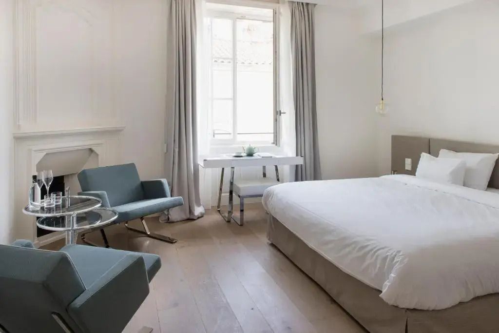 Helles Zimmer mit Doppelbett und Sitzbereich in moderner, minimalistischer Einrichtung