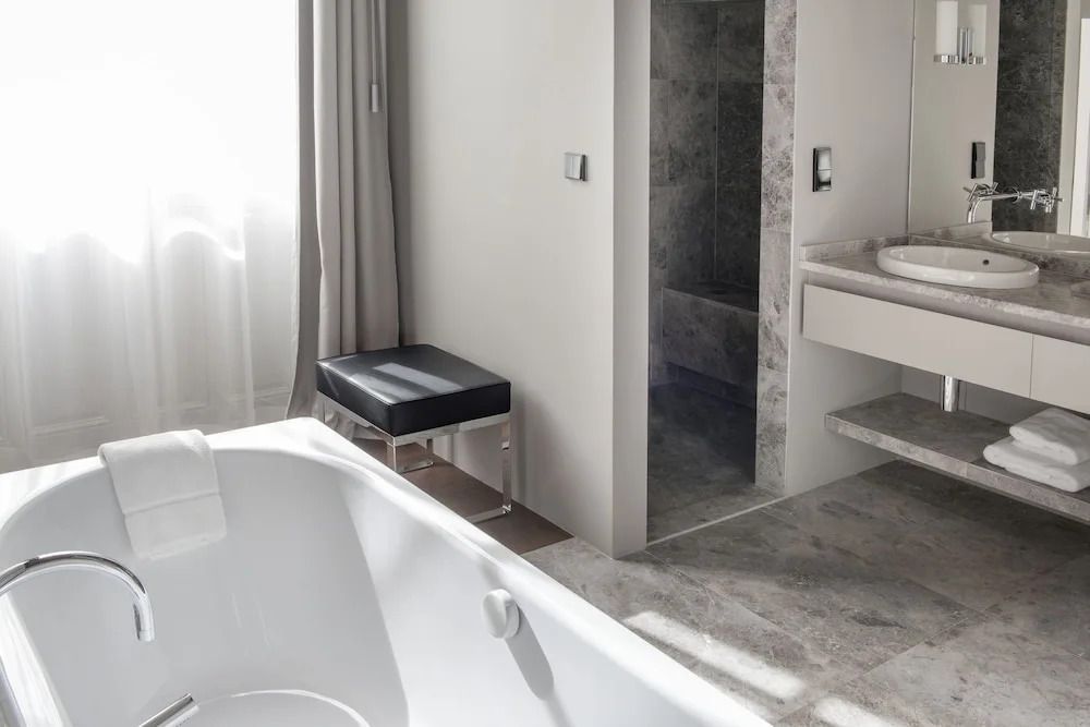 Luxuriöses Badezimmer mit Steinverkleidung und Badewanne im Hotel de Tourrel