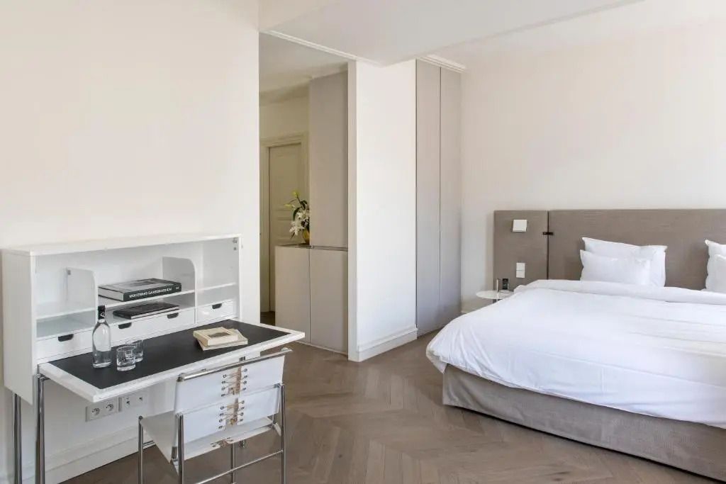 Eleganter Schlafbereich mit weißer Bettwäsche und Schreibtisch im Hotelzimmer