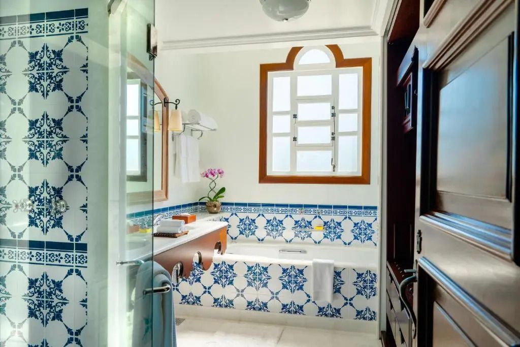 Helles Badezimmer in Deluxe-Suite mit blauen Fliesen und großem Fenster