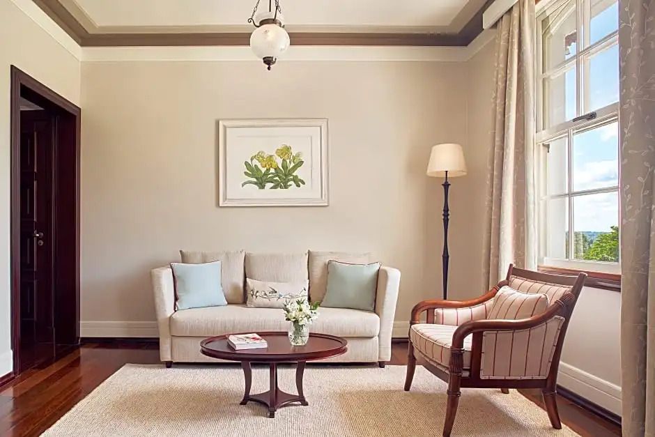 Wohnbereich mit Sofa und Sessel in neutralen Farben und stilvoller Beleuchtung