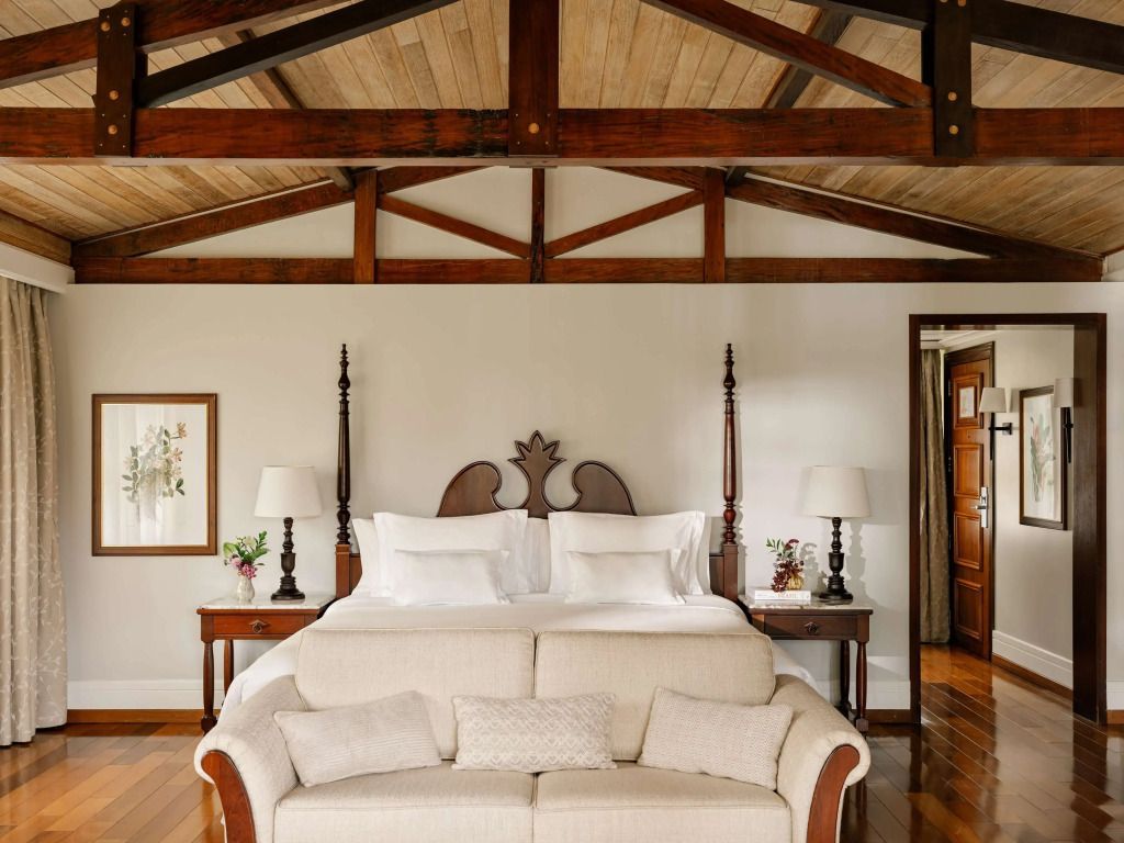 Luxuriöses Schlafzimmer mit freiliegenden Holzbalken und gemütlichem Sofa.