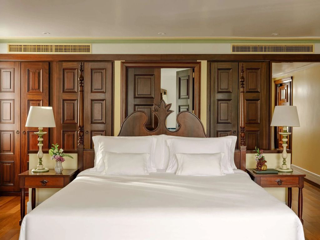 Großes Bett mit kunstvollen Holzdetails und luxuriöser Bettwäsche.