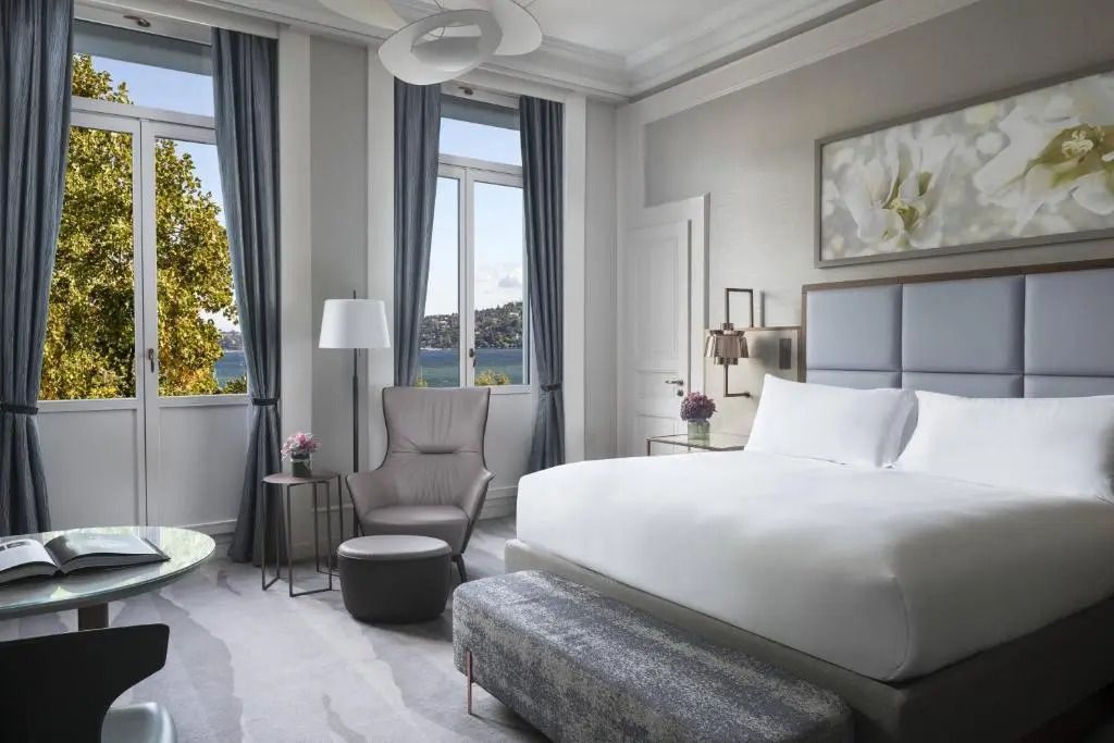 Helles Deluxe Zimmer mit großzügigem Bett und Seeblick im Ritz-Carlton Genf.