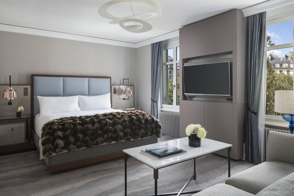 Helles Schlafzimmer mit Doppelbett, stilvollem Dekor und großem Fernseher.