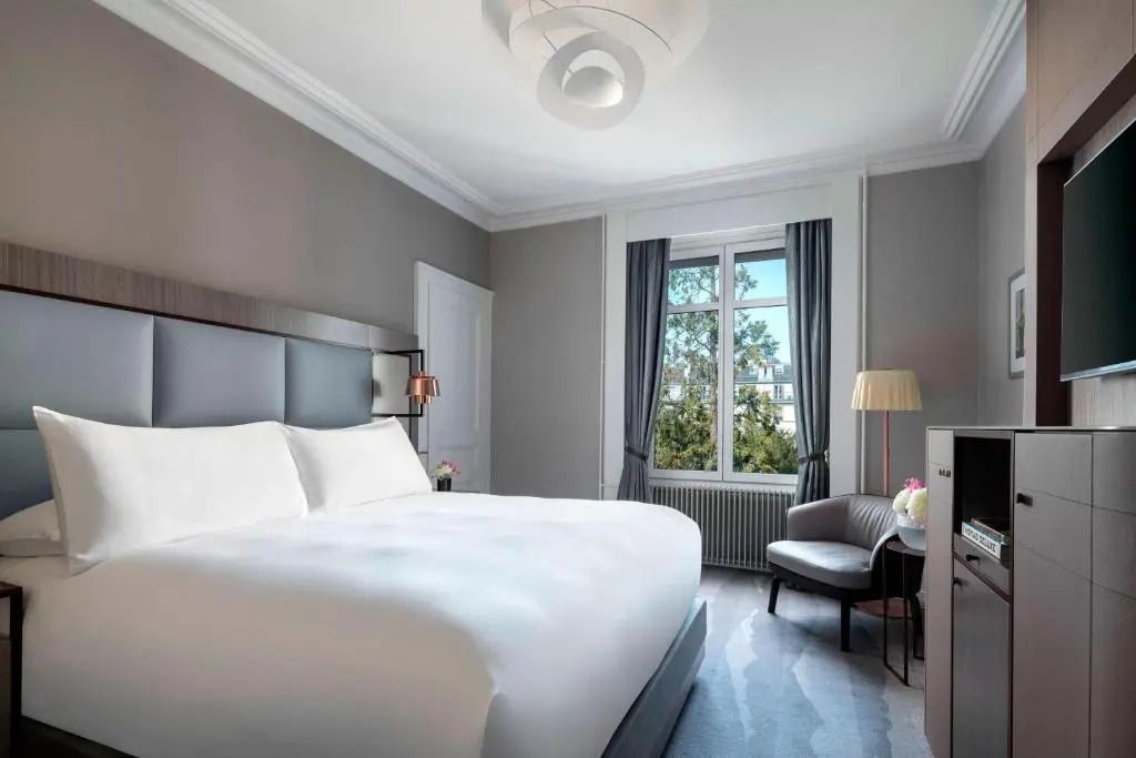 Geräumiges Doppelzimmer mit großem Bett und Aussicht auf Garten im Ritz-Carlton Genf.