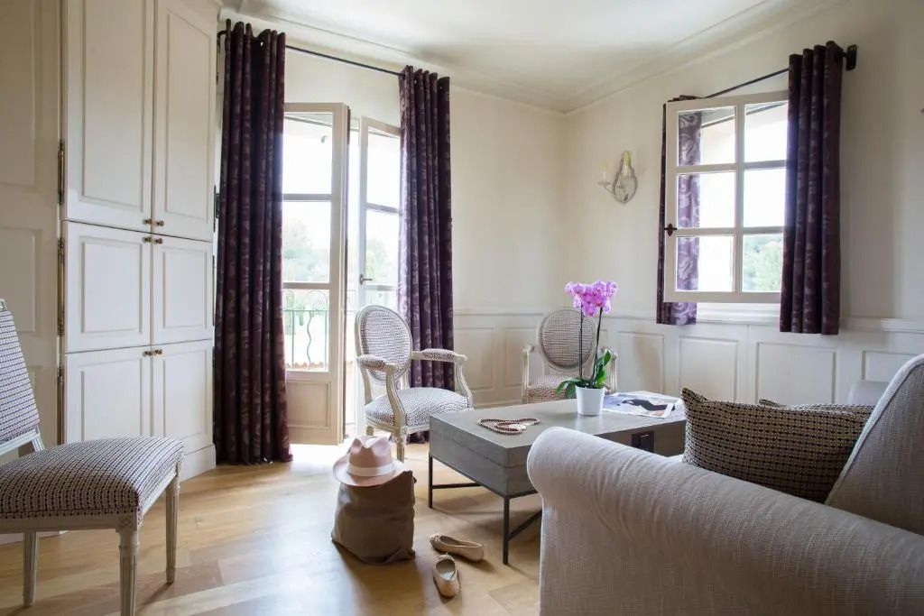 Wohnbereich der Suite mit eleganter Einrichtung und Fenstern mit Vorhängen.
