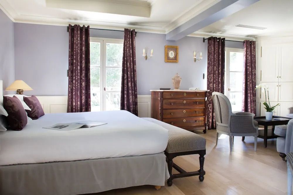 Elegantes Schlafzimmer in einer Junior-Suite mit großem Bett, Balkon und klassischen Möbeln.